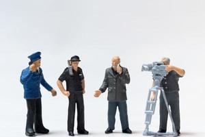 Miniatur-Nachrichtenreporter mit Mikrofon und Kameramann, der Polizisten interviewt foto