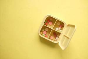 Nahaufnahme von medizinischen Pillen in einer Pillendose auf gelbem Hintergrund foto
