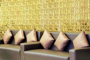 passendes braunes Sofa mit goldenem thailändischem Kunstmusterhintergrund. foto