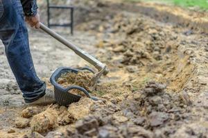 gärtner gräbt den boden mit seiner ausrüstung für die gartenarbeit und bereitet land für die bepflanzung vor. foto