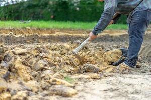 gärtner gräbt den boden mit seiner ausrüstung für die gartenarbeit und bereitet land für die bepflanzung vor. foto