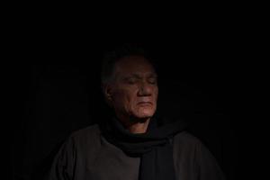 dunkles, launisches, zurückhaltendes Porträt eines reifen Mannes, der sich in tiefen Gedanken entspannt foto