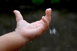 Kinderhand spielt mit Regentropfen. foto