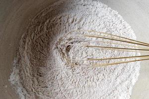 Mischen von Gewürzen aus trockenen Zutaten in Mehl in einer großen Rührschüssel flach liegend foto