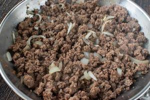 gekochter hamburger mit zwiebeln in der pfanne flach liegend foto