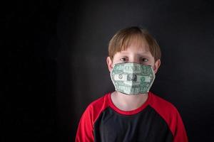 die tatsächlichen Kosten einer Pandemie mit medizinischer Maske aus Geld im Gesicht des Kindes foto