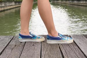 Segeltuchturnschuhe an den Füßen auf der Holzbrücke foto