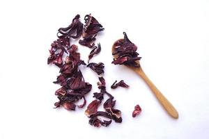 Rote getrocknete Hibiskusblütenblätter in einem kleinen Holzlöffel, gesundes Getränk mit Blumentee, umweltfreundliches Konzept foto