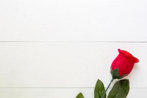 geschenk mit roter rosenblume auf holztisch, 14. februar des liebestages mit romantischem, valentinstag-feiertagskonzept, draufsicht. foto