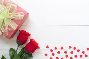 Präsentgeschenk mit roter Rosenblume und Geschenkbox mit Schleifenband und Herz auf Holztisch, 14. Februar des Liebestages mit romantischem, valentinischem Urlaubskonzept, Draufsicht. foto