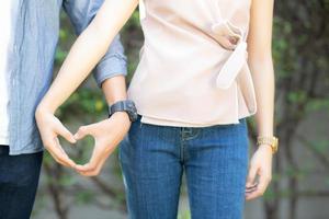 nahaufnahme des glücklichen paares, das spaß macht, gestenherzform mit der hand im freien zusammen zu machen, mann und frau mit dem beziehungsgefühl der liebe mit symbol und zeichen, liebhaber und romantischem konzept. foto