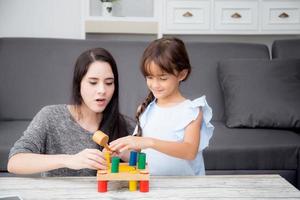 mutter und kind spielen zusammen spielzeug im wohnzimmer zu hause, kind mit der entwicklung des lernens für die bildung mit aktivität mit der familie, mutter, die tochter mit spaß und geschick im zeitvertreib unterrichtet. foto