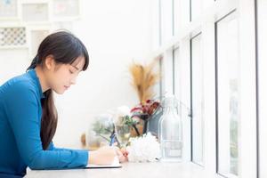 schönes porträt junge asiatische schriftstellerin, die auf notizbuch oder tagebuch mit glücklichem schreibt, lebensstil asiatischer mädchen ist studentin, weibliche planungsarbeit, bildung und geschäftskonzept. foto