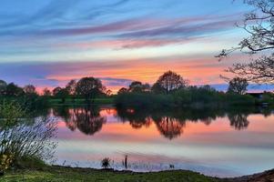 schöne Sonnenuntergangslandschaft an einem See mit spiegelnder Wasseroberfläche