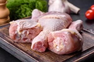 drei Beine rohes Hähnchen mit Gewürzen und Kräutern auf einem Holzschneidebrett foto