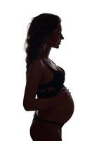 Eine junge weiße schwangere Frau ist im neunten Monat auf hellem Hintergrund schwanger foto