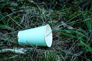 Kaffeetasse aus recyceltem Papier, die im Wald auf Gras liegt foto