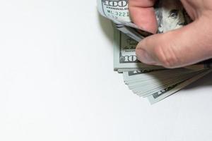 Ein Mann zählt 100-Dollar-Scheine mit der Hand auf weißem Hintergrund. foto