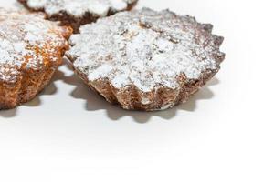 Kleine süße Cupcakes mit Zuckerstreuseln auf weißem Hintergrund. foto