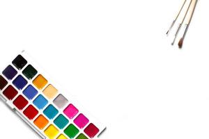 eine Palette von achtzehnfarbigen Wasserfarben und Pinseln auf weißem Hintergrund mit Platz für Text. foto