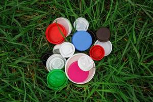 bunte Plastikflaschenverschlüsse auf dem grünen Gras. ehrenamtliche wohltätigkeitsveranstaltung gute deckel, um verwaisten kindern zu helfen. foto