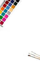 eine Palette von achtzehnfarbigen Wasserfarben und Pinseln auf weißem Hintergrund mit Platz für Text. foto