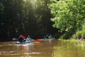 Kajaktour für die Familie. mann und frau und älteres paar senior und seniora ruderboot auf dem fluss, eine wasserwanderung, ein sommerabenteuer. umweltfreundlicher und extremer Tourismus, aktiver und gesunder Lebensstil foto