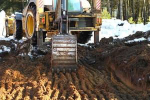 Bulldozer-Eimer-Nahaufnahme gräbt eine Grube für den Bau. das Fundament des Hauses, Erdarbeiten. der bagger schaufelt mit einem eimer die erde aus. landwirtschaft, bauernhof foto