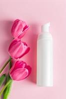 spa-hautpflegeprodukte auf rosa hintergrund. Naturkosmetik und rote Tulpen. foto