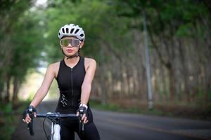 glückliche radsportlerin bereitet sich auf fahrradfahren auf der straße, straße, mit hoher geschwindigkeit für übungen, hobbys und wettbewerbe auf professionellen tour vor foto