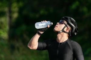 Radfahren Wasser trinken nach dem Fahrradfahren auf der Straße, Straße, mit hoher Geschwindigkeit für Übungshobby und Wettbewerb auf professioneller Tour foto