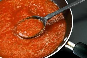 Tomatensoße wird als Spaghetti oder Pasta im italienischen Stil in einer schwarzen Pfanne auf schwarzem Hintergrund zubereitet.Nahaufnahme foto