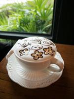Cappuccino mit frischem Milchschaum und Latte Art in einem weißen Keramikglas auf einem Holztisch in einem Café. foto