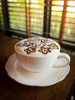 Cappuccino mit frischem Milchschaum und Latte Art in einem weißen Keramikglas auf einem Holztisch in einem Café. foto