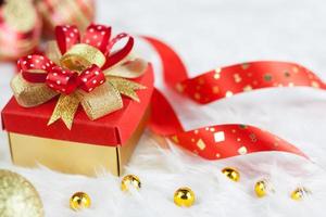 gold-geschenkbox der frohen weihnachten mit roten bändern auf weißem nerzbaumwollhintergrund. wählen sie fokus und kopieren sie platz für ihren text. weihnachts- und valentinsgrußkonzept foto