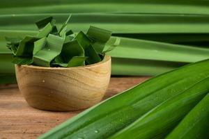 pandan und pandanblätter in einer holzschale, die für pandansaft oder pandankuchen zum kochen oder getrockneten vor dem kochen zubereitet wird. im studio gedreht foto