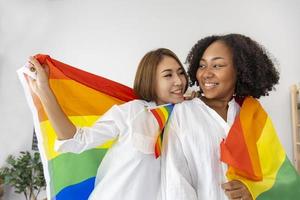 ein paar gleichgeschlechtlicher ehen aus unterschiedlichen rassen, die die lgbtq-regenbogenfahne für den stolzmonat halten, um die gleichstellung und unterschiede des homosexuellen und diskriminierungskonzepts zu fördern foto