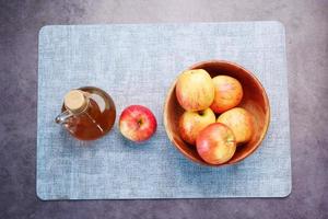 Draufsicht auf Apfelessig in Glasflasche mit frischem grünem Apfel auf dem Tisch foto