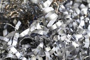 Recycling von Stahlschrott. Aluminiumspanabfälle nach der Bearbeitung von Metallteilen auf einer CNC-Drehmaschine. Nahaufnahme verdrehte Spiralstahlspäne. kleine Rauheit Schärfe, foto