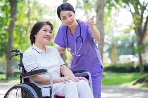 asiatische Krankenschwester, die sich um eine Patientin mittleren Alters im Park kümmert foto