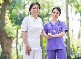 asiatische Krankenschwester, die sich um eine Patientin mittleren Alters im Park kümmert foto