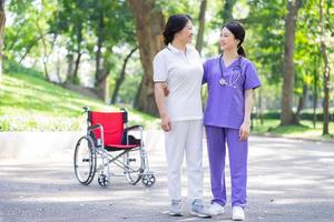 asiatische Krankenschwester, die sich um eine Patientin mittleren Alters im Park kümmert foto