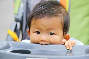 asiatisches baby, das auf kinderwagen sitzt. süßer Junge im Kinderwagen. foto