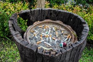 geräucherte Zigarettenstummel in einem schmutzigen Aschenbecher großer Mülleimer foto