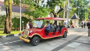 sukoharjo - 24. mai 2022 - asiatischer tourist, der mit einem tourismusfahrer in einem roten oldtimer sitzt foto