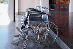 Nahaufnahme einer Reihe leerer Rollstühle, die im Freien parken und für ältere Menschen und behinderte Passagiere vorbereitet sind foto