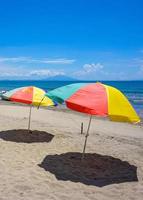 bunter Regenschirm am Sandstrand unter blauem Himmel. sommerferien reisen. tropische urlaubsreise. kostenloses Foto