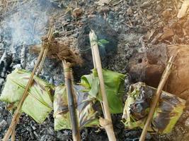Kochen, indem Bananenblätter eingewickelt und über Feuer gegrillt werden. foto