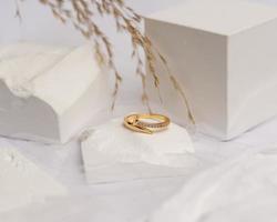Ehering auf weißem Stein. Der Schmuckring kann präsentiert und verkauft werden. Der Ehering ist ein Zeichen der Liebe des Paares. Perlen und Diamanten vervollständigen die Schönheit des Rings. Fokusunschärfe. foto