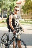 Porträt eines jungen Mannes mit einem Fahrrad auf der Straße. schwarzes T-Shirt mit Aufdruck 23 foto